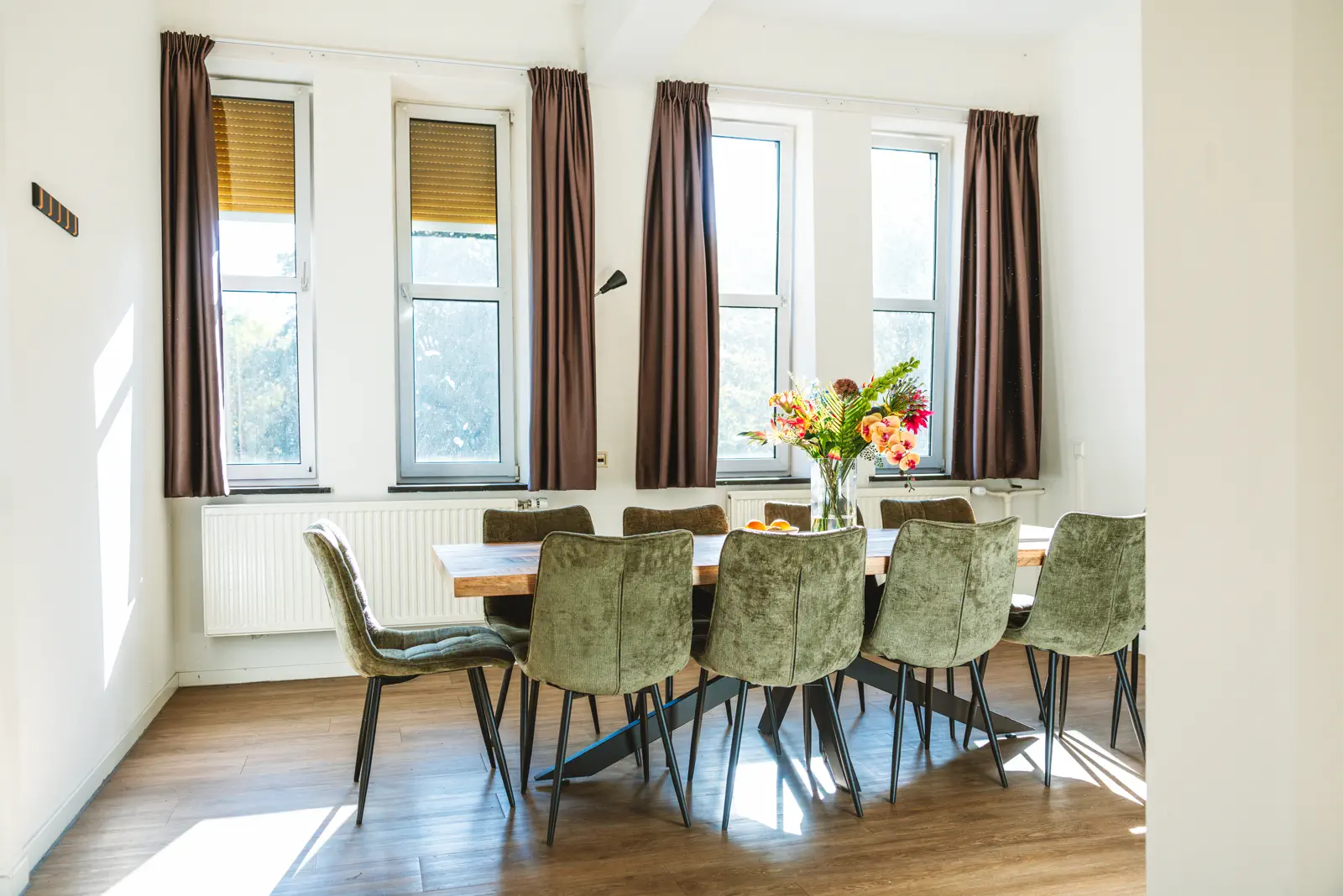 Lange eettafel met stoelen bij de ramen