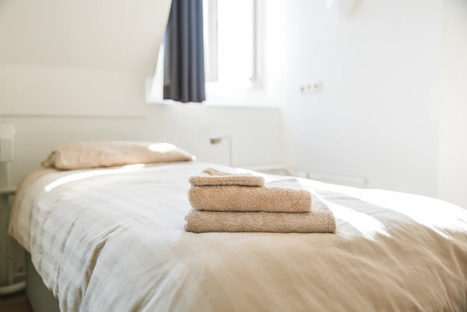 Opgemaakt bed met handdoeken erop