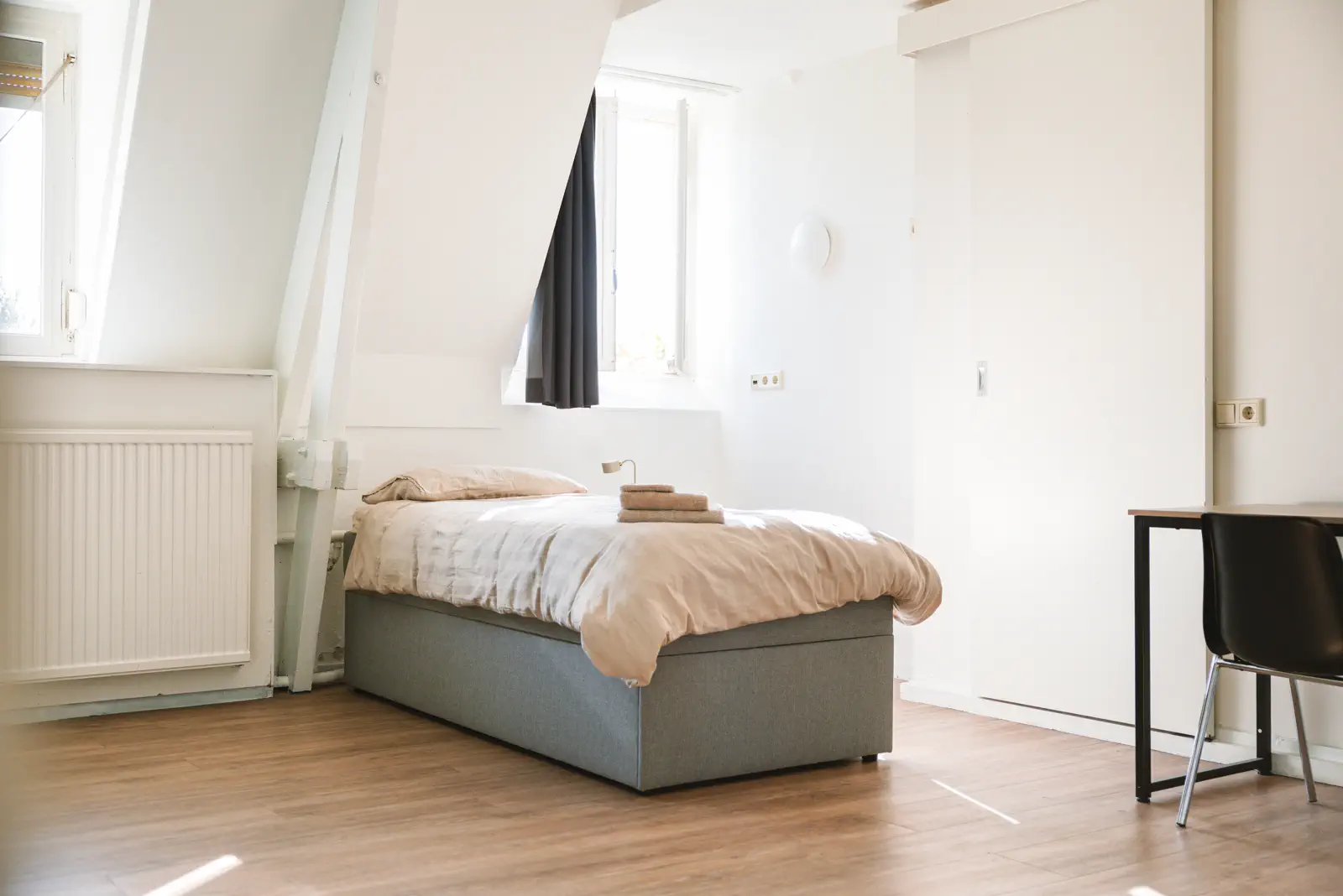 Slaapkamer met eenpersoonsbed en grote ramen